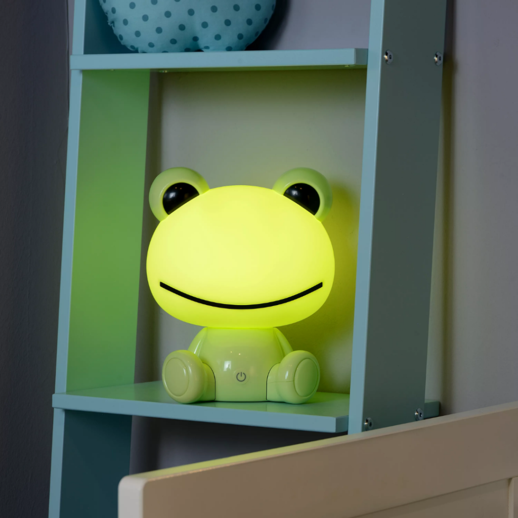 Groene kikker tafellamp met zacht geel licht op kinderkamerplank
