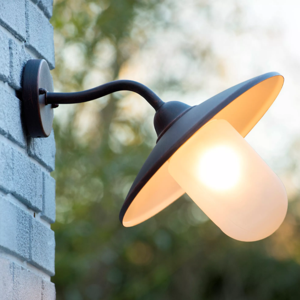 Buitenwandlamp roestkleurig met matglas kap aan witte muur