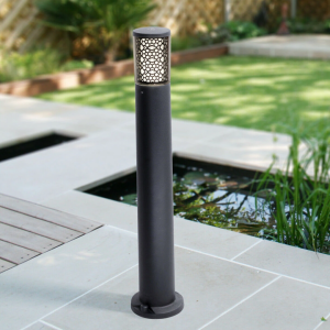 Zwarte tuinpaalverlichting met decoratief patroon en warmwit licht naast vijver