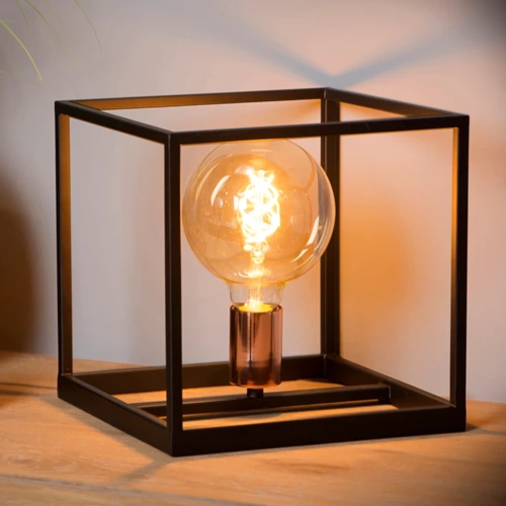 Zwarte vierkante tafellamp met open metalen frame en warme gloed op houten