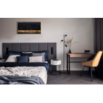 Zwarte vloerlamp met drie verstelbare spots naast bed en houten bureau.