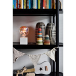 Glazen LED-lamp met iriserende gloed op zwarte wandplank met decoratie.