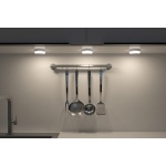 Drie ronde pucklights verlichten keukenwand met metalen keukengerei aan stang.