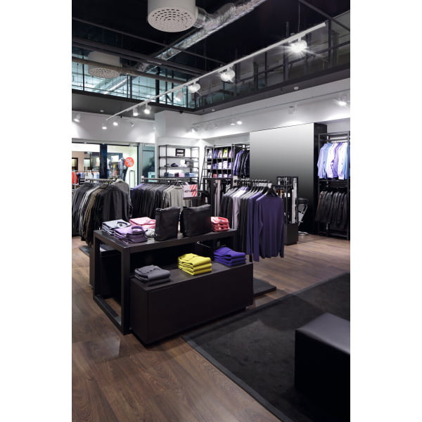 Witte railspots verlichten moderne kledingwinkel met rekken en gevouwen truien