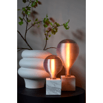 Twee glazen tafellampen met wit marmeren voet naast witte vaas met tak.