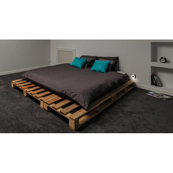 Witte stekkerlamp met dag en nacht sensor brandt naast bed in slaapkamer