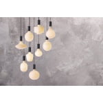 Hangende opaalglazen lampen in diverse vormen tegen grijze betonnen muur