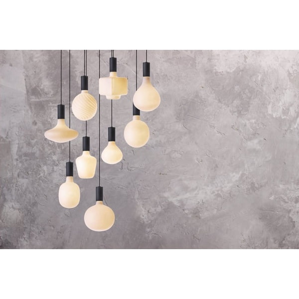 Hangende opaalglazen lampen in diverse vormen tegen grijze betonnen muur