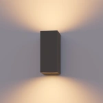 Grijze buitenwandlamp met lichtstralen omhoog en omlaag tegen muur