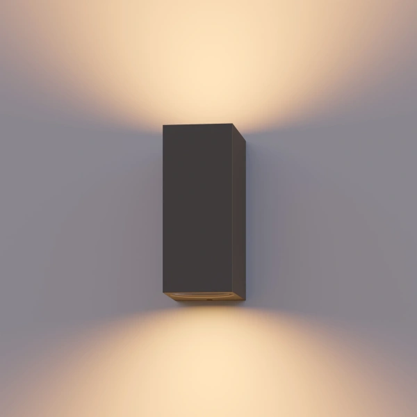 Grijze buitenwandlamp met lichtstralen omhoog en omlaag tegen muur