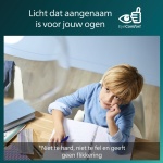 Jongen schrijft in schrift aan bureau met zacht binnenlicht boven zich