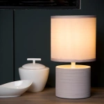 Beige ronde tafellamp met stoffen kap op houten tafel in interieursetting