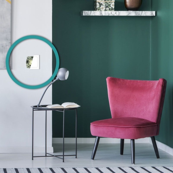 ecodim10-zwave-sfeer Wanddimmer met zichtbare module naast roze stoel en bijzettafel