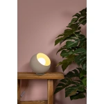 Ronde beige tafellamp op houten tafel naast groene plant