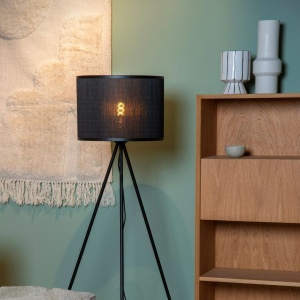 Zwarte vloerlamp met ronde kap en tripod voet in woonkamerhoek