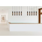 Zwarte cilindervormige hanglampen boven modern wit interieur met houten details