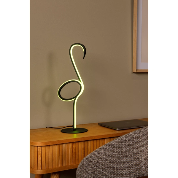 Flamingo tafellamp met zwarte basis en geelgroen licht op houten bureau