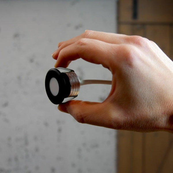 Mini inbouwspot zwart met ronde rand vastgehouden tussen vingers