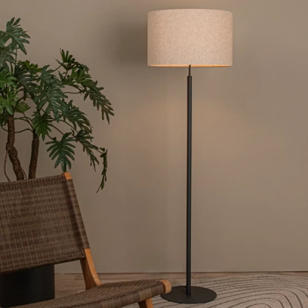 Beige vloerlamp met stoffen kap en zwarte metalen voet in woonkamerinterieur