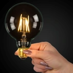 Globe ledlamp E27 7W warmwit licht in hand gehouden