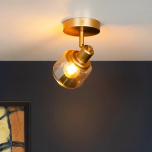 Goudkleurige messing plafondspot met één lichtpunt en glazen kap in interieur