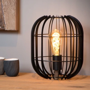 Zwarte metalen tafellamp met open kooi en warm licht op houten tafel