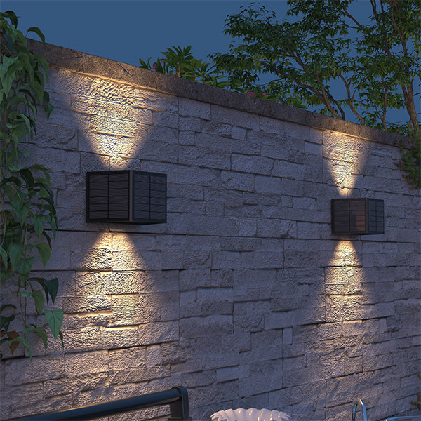 Zwarte solar wandlamp met up en down licht op stenen tuinmuur