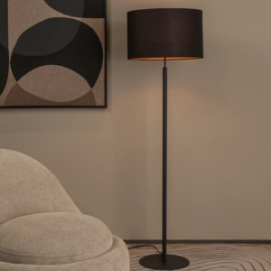 Zwarte Scandinavische vloerlamp met stoffen kap naast beige fauteuil in woonkamer
