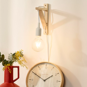 Scandinavische houten wandlamp met zwarte fitting boven klok en rode vaas