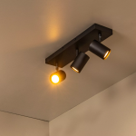 Zwarte moderne plafondspot met drie verstelbare lichtspots in warme verlichting