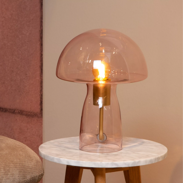 Roze glazen paddenstoel tafellamp met messing fitting op marmeren bijzettafel