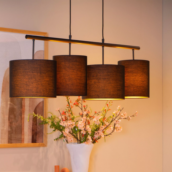 Zwarte Scandinavische hanglamp met vier stoffen kappen boven eettafel in warme setting