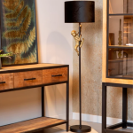 Zwarte vloerlamp met gouden aapfiguur naast houten meubel in woonkamer
