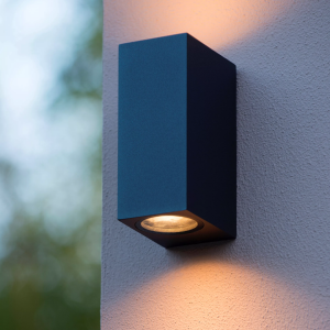 Zwarte up down wandlamp met warm licht tegen buitenmuur