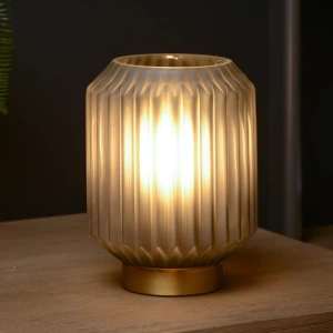 Grijze glazen tafellamp met warme gloed op houten oppervlak