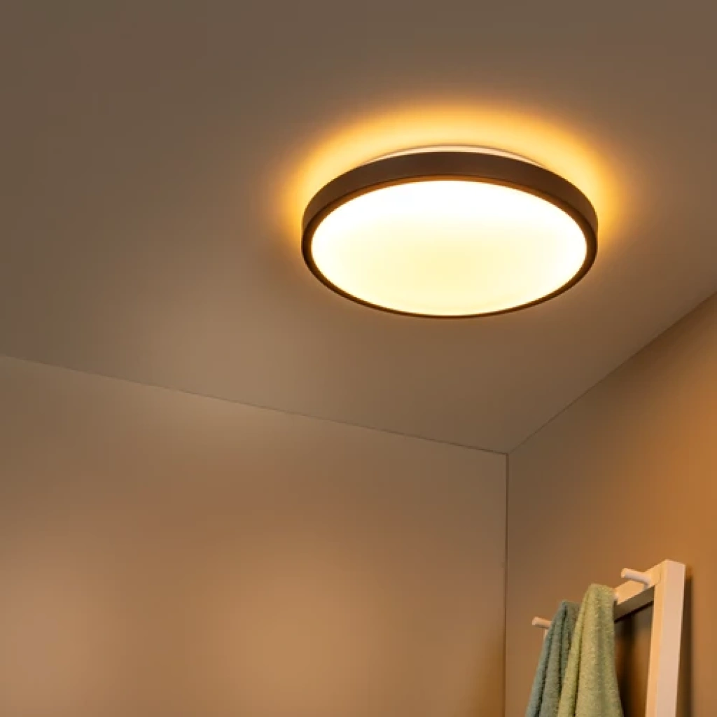 Zwarte ronde plafonniere met warm licht en bewegingssensor aan plafond
