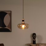 Amberkleurige glazen hanglamp met ronde kap en warm licht boven houten tafel