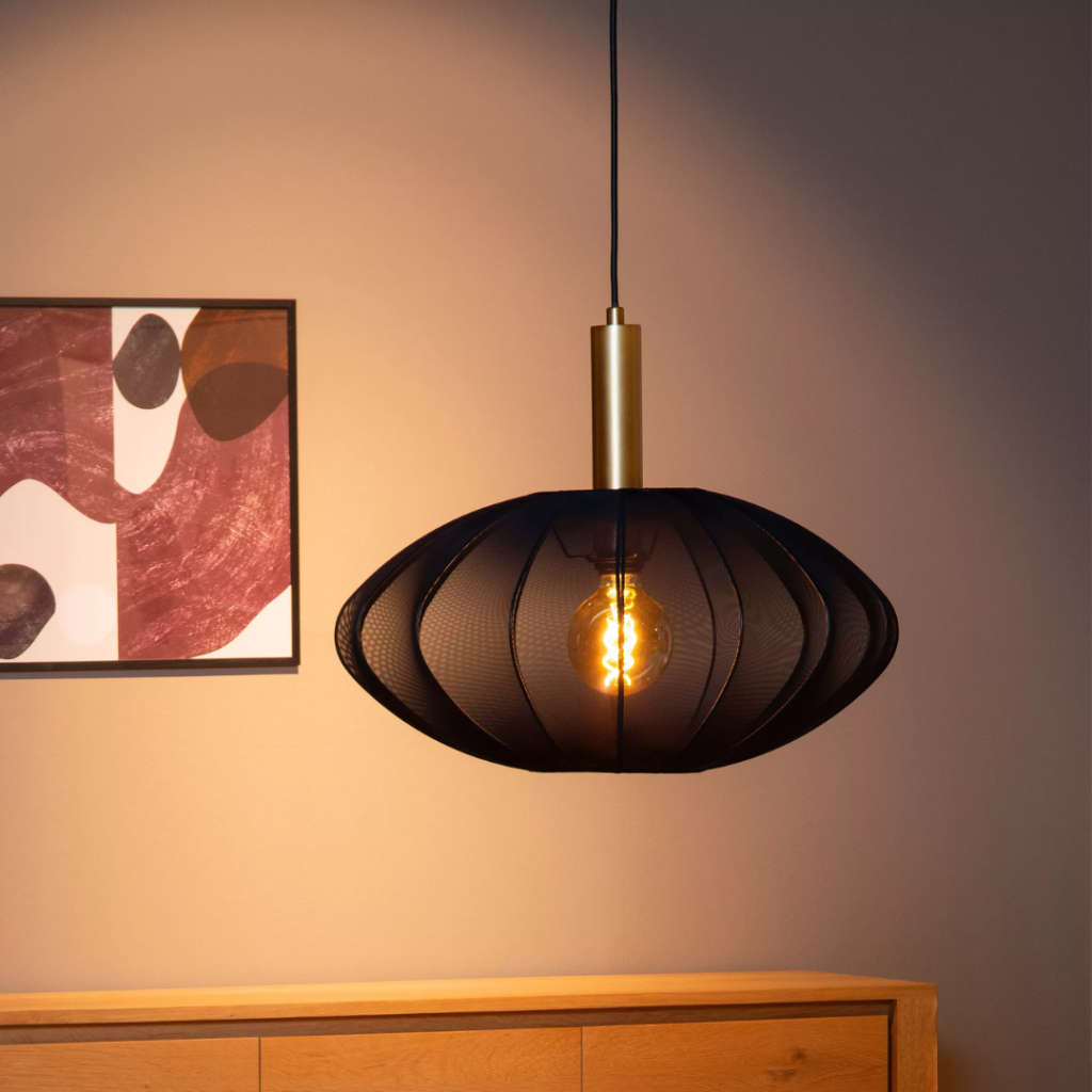 Zwarte Scandinavische hanglamp met goudaccent en warme gloed boven houten dressoir