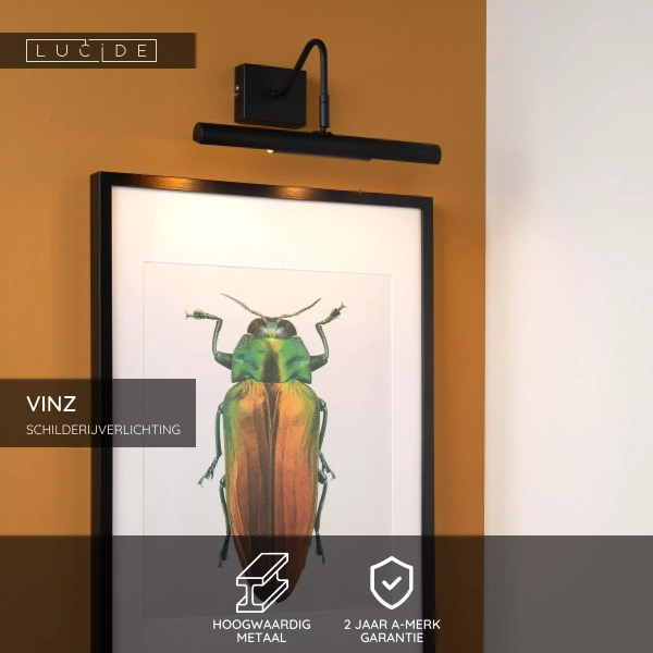 Zwarte metalen schilderijverlichting boven ingelijst kunstwerk aan okergele muur