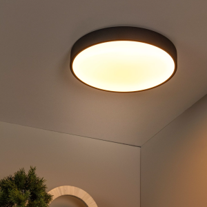 Zwarte ronde plafonnière met warmwit licht in moderne interieurhoek