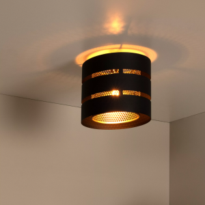 Zwarte ronde plafondlamp met geperforeerde kap en warm lichtpatroon op plafond