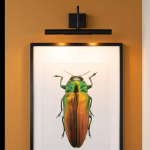 Zwarte schilderijverlichting met twee G9-lichtpunten boven ingelijst kunstwerk aan muur