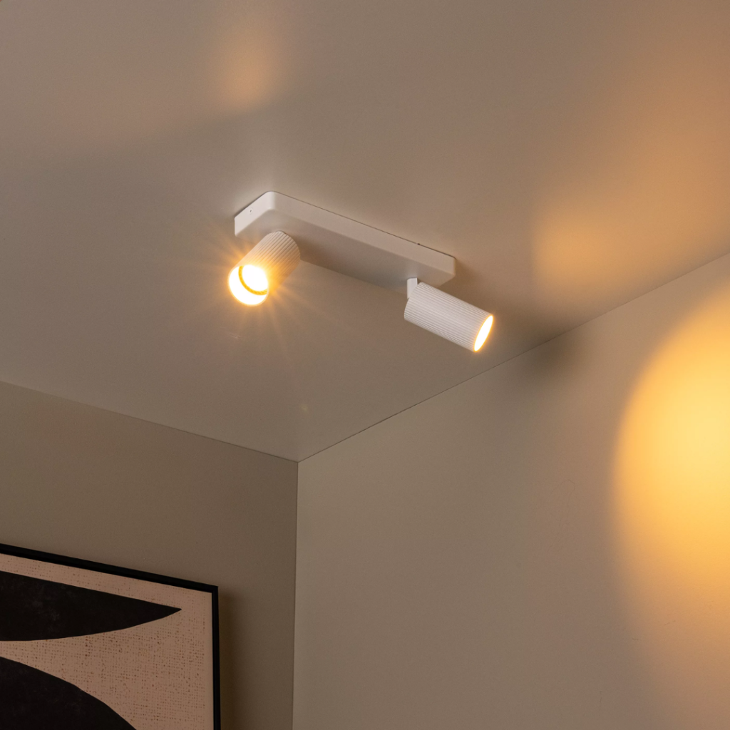 Witte moderne plafondspot met twee richtbare lichtpunten in warme verlichting