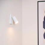 Witte moderne wandlamp met geribbelde spotkop verlicht muur in interieur