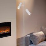 Witte moderne vloerlamp met twee verstelbare spots naast grijze bank en haard