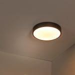 Zwarte ronde plafonnière met warmwit licht in moderne interieurhoek