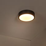 Zwarte ronde plafonnière met warmwit licht in moderne interieurhoek