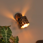 Zwarte metalen wandlamp met opengewerkt patroon en warm licht in woonkamer