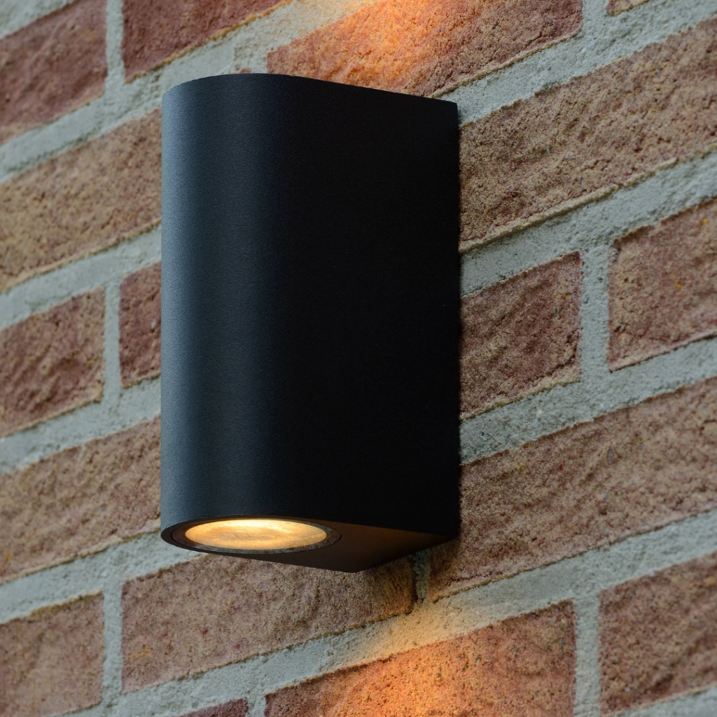 Zwarte moderne wandlamp met up en down licht op bakstenen buitenmuur