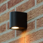 Zwarte moderne wandlamp met neerwaarts licht op buitenmuur